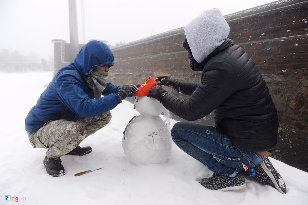 Hai bạn trẻ đang vui vẻ nặn người tuyết tại Sapa.