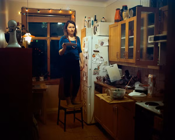 Katrín, 36 tuổi, mang đĩa thức ăn đi hâm nóng sau khi cho hai con của cô (một bé 7 tuổi và một bé 4 tuổi) đi ngủ. Được biết, Katrín vừa là một cô giáo mầm non vừa đang theo học.