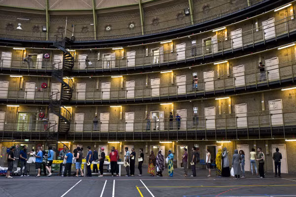 Di dân và người tị nạn xếp hàng nhận bữa trưa trong nhà tù De Koepel ngày 20/4.