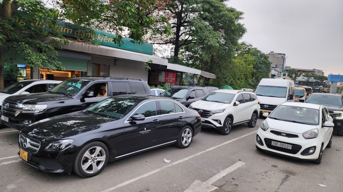 Các xe xếp hàng dài từ ngoài cổng vào trong khu vực đăng kiểm. Một nhân viên đăng kiểm phải thực hiện nhiệm vụ điều tiết giao thông, sắp xếp vị trí đỗ xe chờ đến lượt cho các tài xế nhằm ổn định TTATGT khu vực đơn vị đăng kiểm.