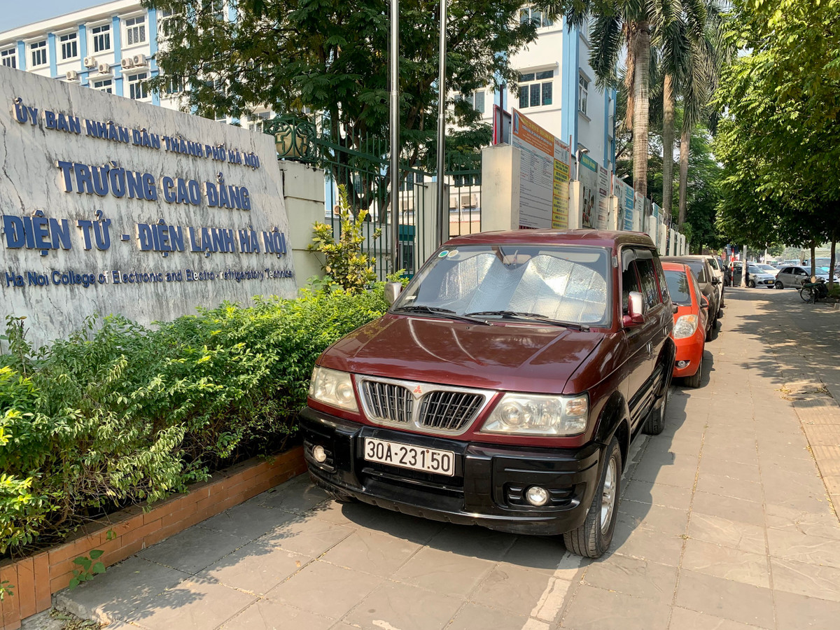 Xe ô tô đỗ, xếp hàng dài trên vỉa hè trước cổng Trường Cao đẳng Điện tử - Điện lạnh Hà Nội (Số 10, đường Nguyễn Văn Huyên, Dịch Vọng, Cầu Giấy).