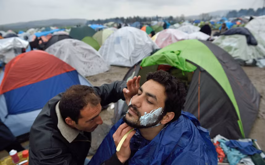 Người đàn ông cạo râu cho bạn của anh trong khu trại tạm bợ.