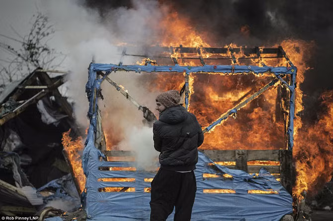 Một người tị nạn dùng bình cứu hỏa dập tắt đám cháy trong trại tị nạn Jungle.