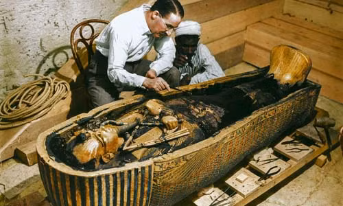 Nhà khảo cổ học Howard Carter và một công nhân Ai Cập kiểm tra quan tài thứ 3 làm bằng vàng được đặt trong 2 chiếc quan tài lớn ở bên ngoài năm 1925.