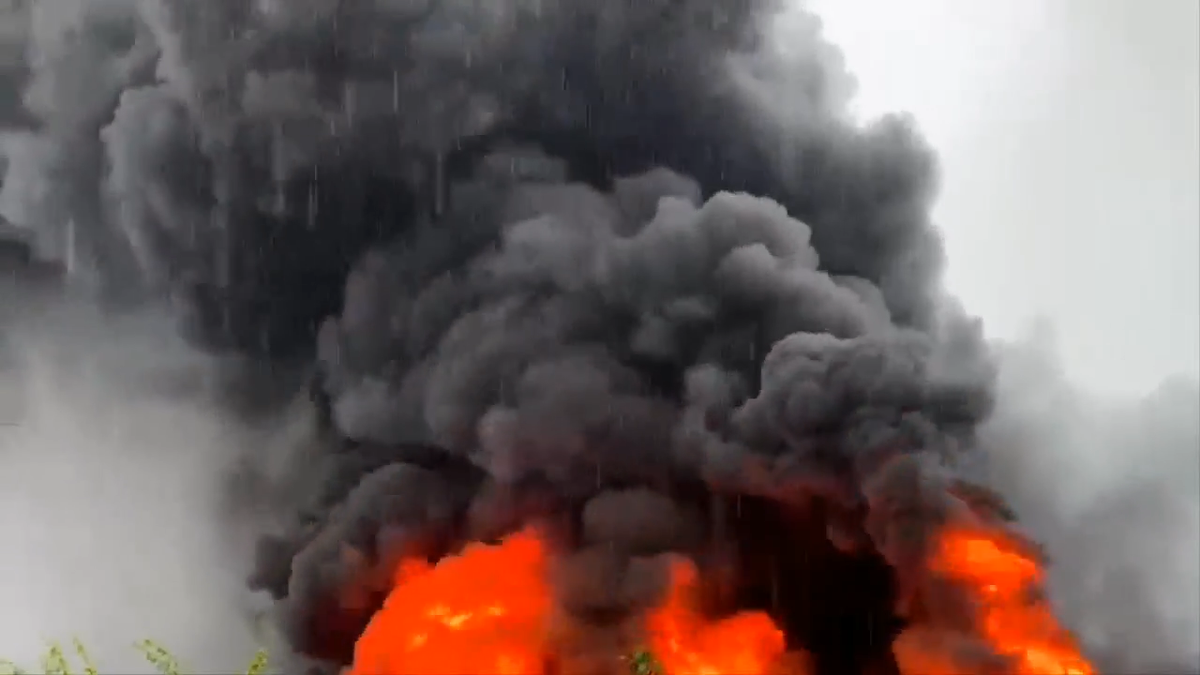 Chỉ vài phút sau, ngọn lửa lớn đã bao trùm cả nhà kho rộng hàng trăm mét vuông. Ngọn lửa cuồn cuộn bùng lên dữ dội dù trời đang có mưa lớn, cột khói cao trăm mét.