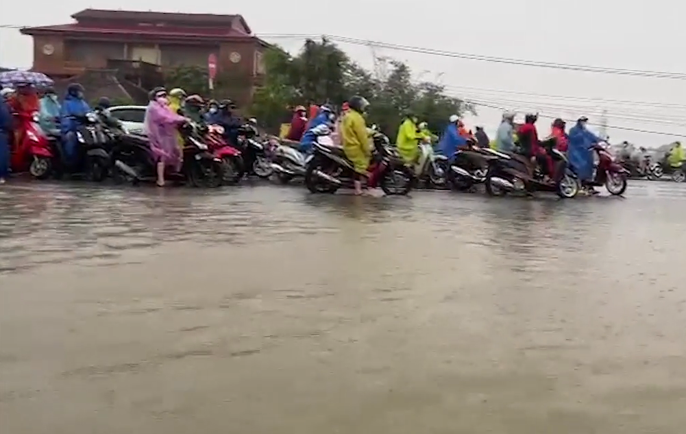 Hàng trăm công nhân khu công nghiệp Tam Thăng (TP Tam Kỳ, tỉnh Quảng Nam) đứng "chôn chân" trên đường, không thể đến chỗ làm vì nước ngập.