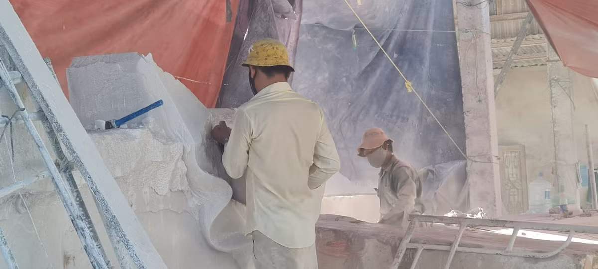 Dù được che tạm bằng bạt, bụi đá vẫn bay mù mịt từ các xưởng sản xuất ra khu vực xung quanh.