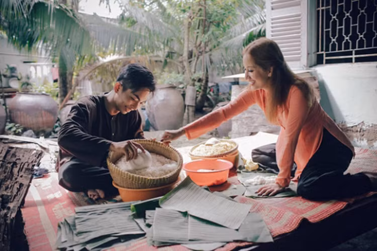 Cặp đôi mặc áo bà ba, tất bật gói bánh chưng chuẩn bị cho ngày Tết Nguyên Đán. Ảnh: VTV