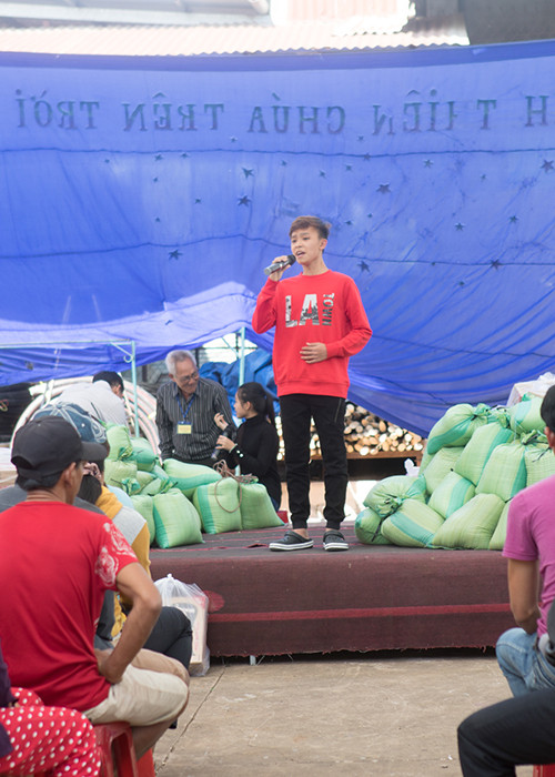 Hình ảnh Hồ Văn Cường biểu diễn ngay tại nơi trao quà với loa và âm thanh thô sơ, sân khấu chỉ là những tấm ván được ghép lên.