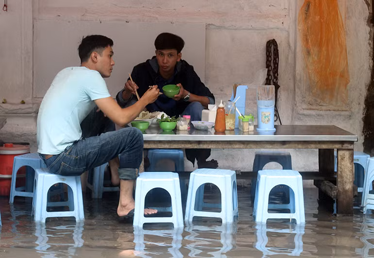 Người Hà Nội ăn uống trong nước ngập.