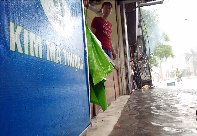 Mực nước càng lúc càng dâng cao trên phố Phố Kim Mã Thượng (phường Cống Vị, quận Ba Đình, TP Hà Nội), người dân phải sử dụng các tấm ván để che chắn.