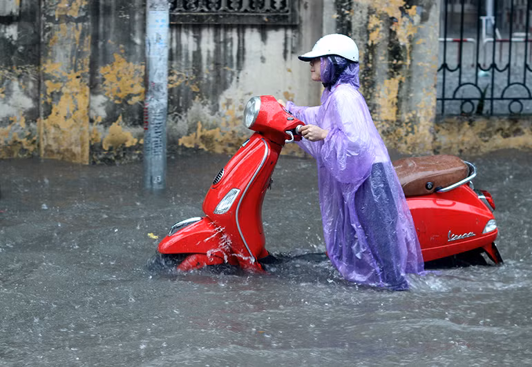 Cô gái cố gắng đẩy chiếc xe chết máy "vượt sông".