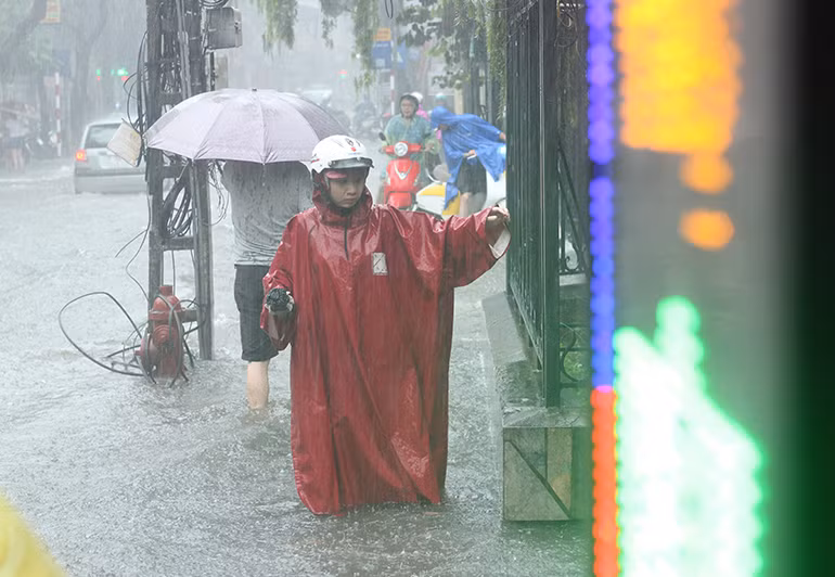 Dù bước bộ nhưng người dân vẫn phải bám vào tường để mò đường đi dưới mưa trên phố Đội Cấn.