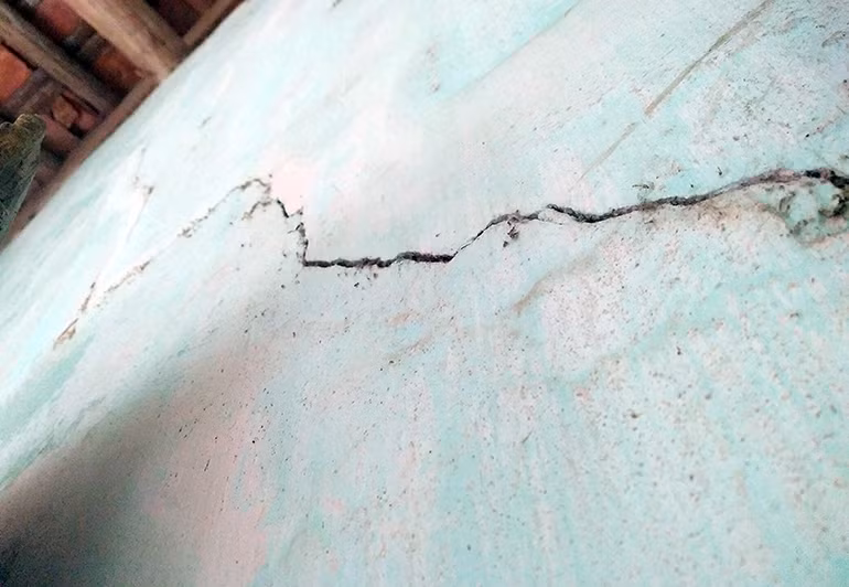 Bên trong bức tường nhà xuất hiện nhiều vết rạn nứt, chạy dài lên tận mái ngói.