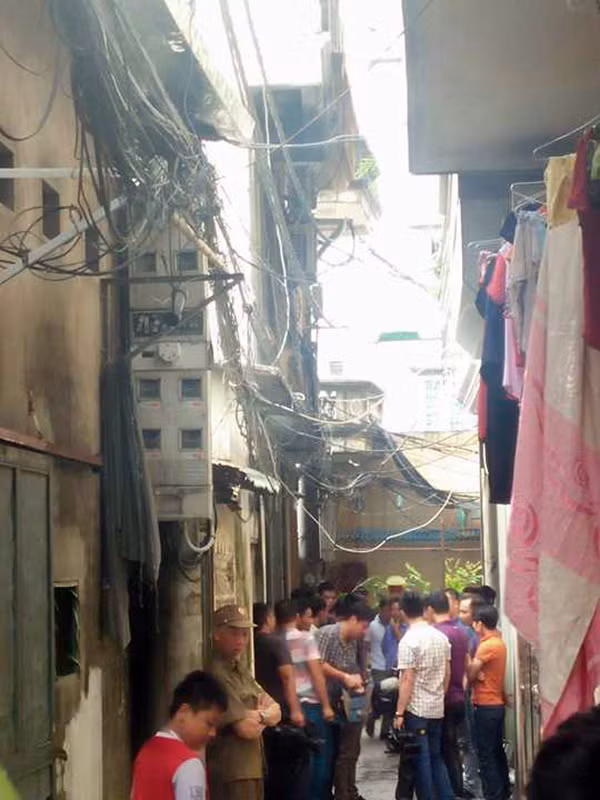 Cảnh sát đang phong tỏa hiện trường vụ cháy để khám nghiệm. Nhiều người tụ tập theo dõi.