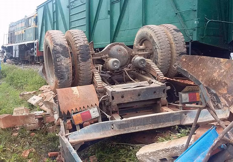 Chiếc xe tải chở gạch bị tàu húc văng ra phía bờ ruộng, nằm phơi bụng lên trời.