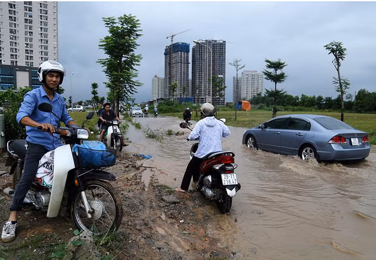 Ô tô bì bõm vượt nước ngập sâu. Trong khi đó, các xe máy nháo nhào leo lên vỉa hè hoặc sát mép đường để tìm lối thoát.