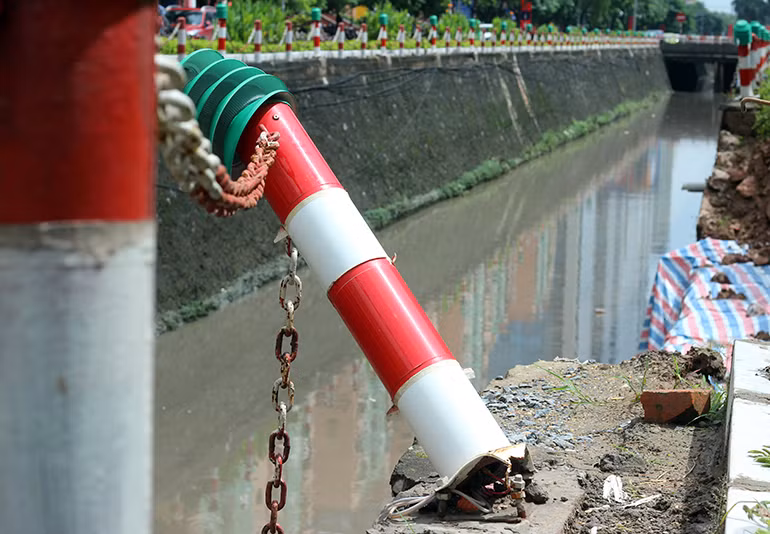 Hàng rào sắt ngăn cách bị gãy đổ do đất sạt lở kéo xuống mương nước.