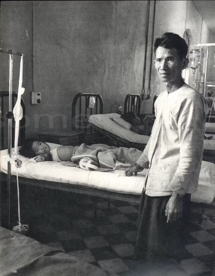 Ánh mắt đau đớn của người cha bên đứa con gái mất cả tay lẫn chân do trúng mìn.