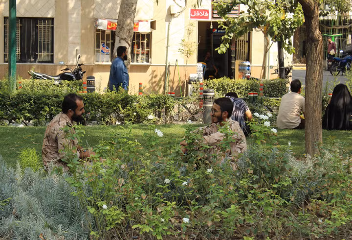 Hai người lính ngồi trò chuyện vào buổi trưa ở một vườn hoa.