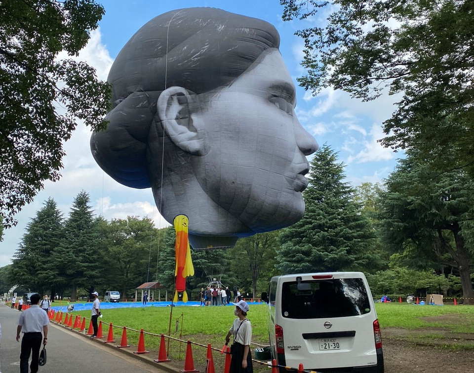 Chiếc khinh khí cầu được các nghệ sĩ đưa tới công viên Yoyogi tại quận Shibuya, thủ đô Tokyo vào sáng sớm 16/7. Khinh khí cầu bay lên không trung lúc 6h sáng, sau khi được bơm đầy hơi nóng. Tác phẩm nghệ thuật này dự kiến bay trên không trung ở thủ đô Tokyo từ 6h-20h mỗi ngày, cho tới 18/7. Ảnh: People Daily.
