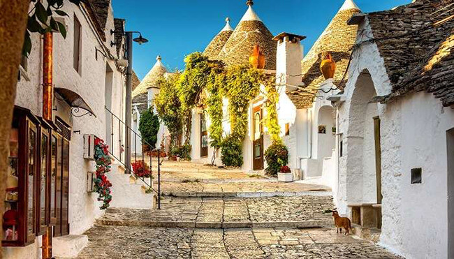 Alberobello, Ý: Các con đường ở đây trông vô cùng đặc biệt bởi sự xuất hiện của trulli, những túp lều bằng đá quét vôi trắng có mái hình nón. Một điểm nhấn khác không thể bỏ qua của con phố đẹp như tranh vẽ này là cảnh hoàng hôn phía xa vô cùng ấn tượng.