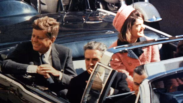 Về sau, Tổng thống Kennedy ngồi xe mui trần cùng vợ - đệ nhất phu nhân Jacqueline Kennedy đến khu vực náo nhiệt Dealey Plaza, thành phố Dallas, bang Texas và bị ám sát.