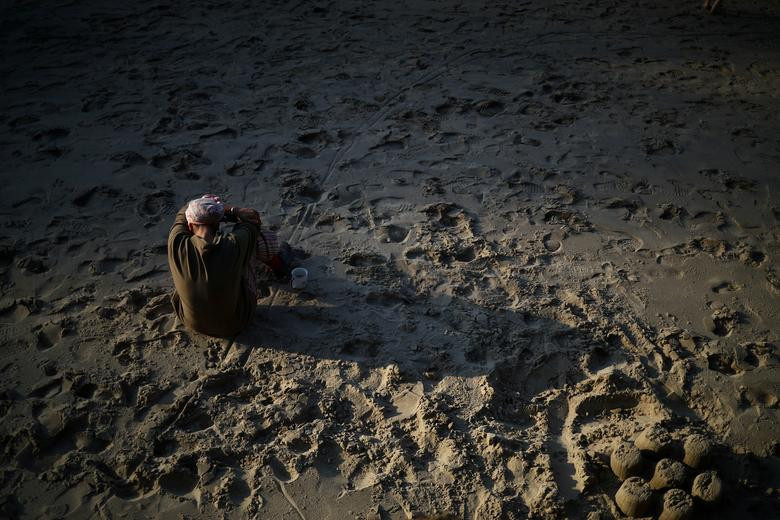 Một người dân ngồi trên bãi cát với cốc cà phê ở Southbank, London, ngày 7/5.