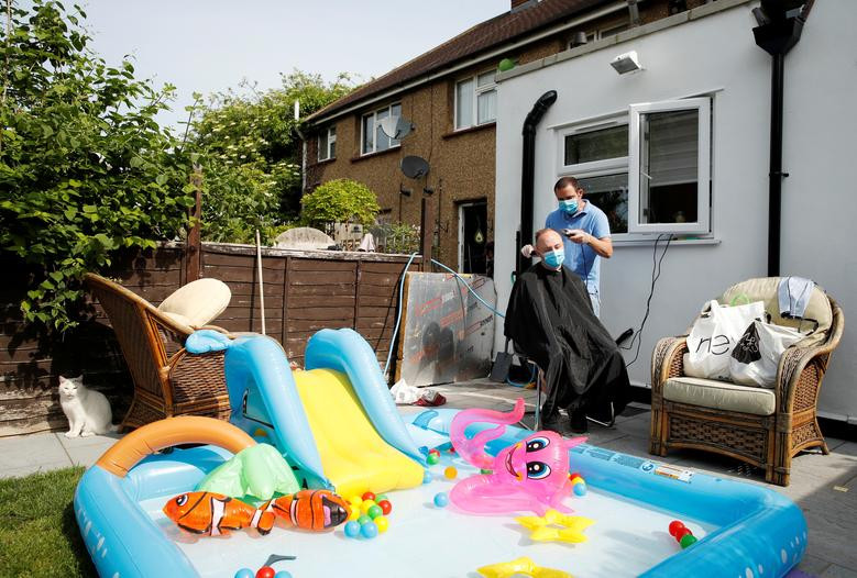 Pavlos đeo khẩu trang cắt tóc cho một người đàn ông trong vườn nhà ở Edmonton ngày 8/5. Được biết, tiệm cắt tóc của Pavlos đã phải đóng cửa để phòng, chống dịch COVID-19. Mời độc giả xem thêm video: WHO chính thức đặt tên cho virus corona mới là SARS-CoV-2 (Nguồn video: VTC1)