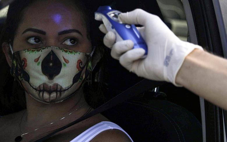 Nhân viên đo thân nhiệt cho một tài xế tại cửa ngõ vào thành phố Niteroi, gần Rio de Janeiro, trong ngày đầu phong tỏa hôm 11/5.