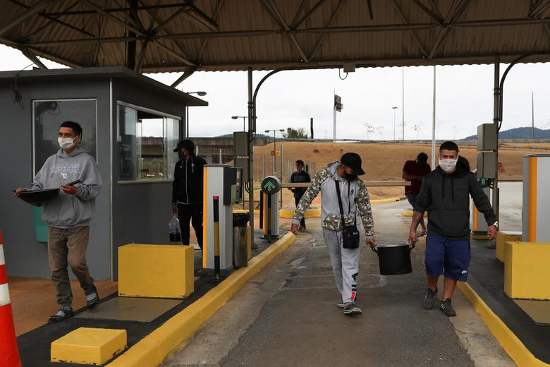 Mọi người khiêng xoong đựng đồ ăn vào bãi đỗ xe của sân bay...