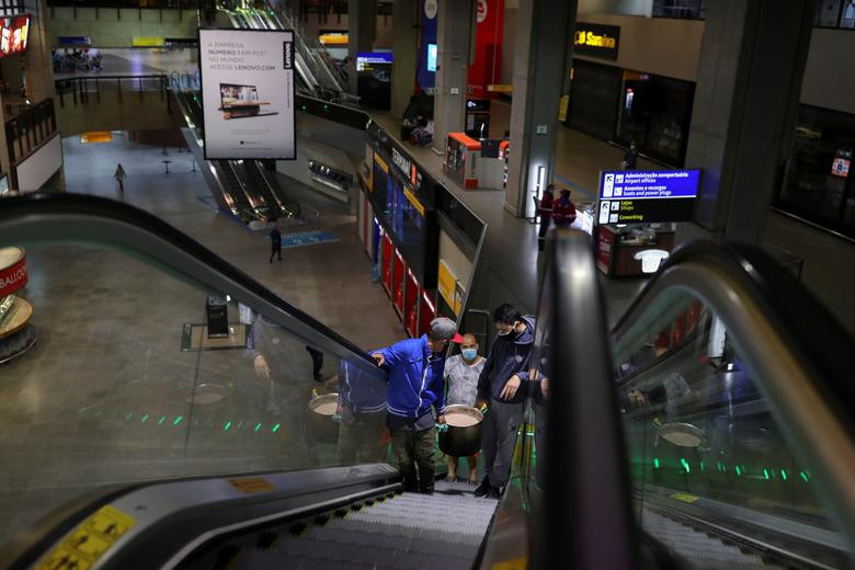 Người đàn ông khiêng xoong đựng đồ ăn trong sân bay.