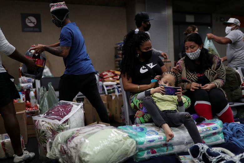 Felicia Restrepo chải đầu cho con gái trong khi mọi người nhận viện trợ nhu yếu phẩm phía sau tại sảnh của sân bay Guarulhos ngày 23/5.