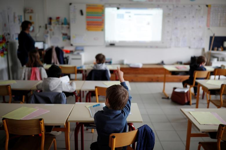 Giáo viên đeo khẩu trang giảng bài trong khi các em học sinh được bố trí ngồi cách nhau trong lớp học của một trường tư thục ở Saint-Sebastien-sur-Loire, gần Nantes, Pháp, ngày 12/5. Được biết, tại Pháp, học sinh tiểu học phải ngồi cách nhau ít nhất 1 mét trong phòng học còn giáo viên phải đeo khẩu trang trong ngày đầu tiên đi học trở lại sau hai tháng trường đóng cửa vì COVID-19.