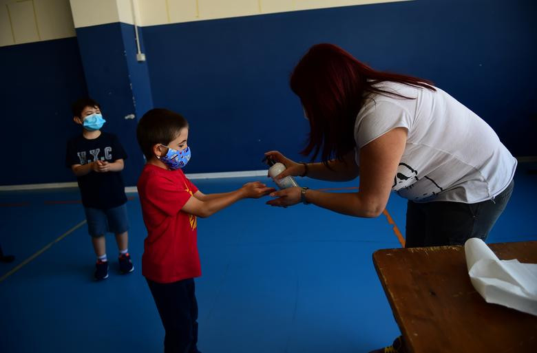 Nhóm học sinh từ 6 đến 10 tuổi được sát khuẩn tay ở lớp học tạm thời trong phòng tập thể dục ở vùng Piedmont, Italy, hôm 12/5.