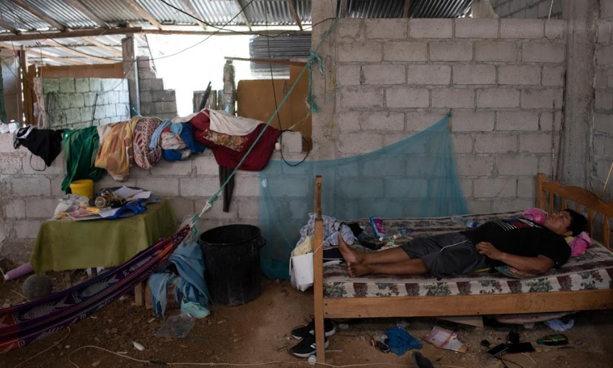 Cristian Jordan, 37 tuổi, bị sốt xuất huyết và có các triệu chứng của COVID-19, nằm trên giường trong nhà ở Puerto Roma.