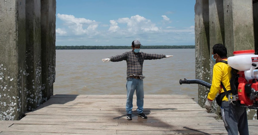 Victoriano, 49 tuổi, được phun thuốc khử trùng sau khi lên bờ tại bến cảng của thị trấn.