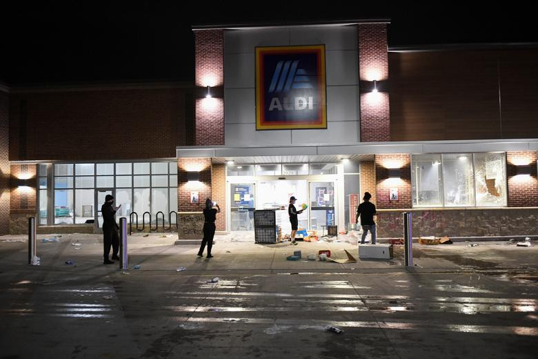 Người biểu tình tập trung bên ngoài một siêu thị Aldi bị cướp phá. Ảnh: Reuters.