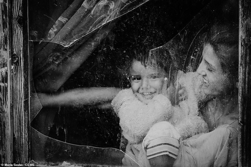 Người mẹ cười hạnh phúc khi bế con nhỏ bên cửa sổ ở Bag, Hungary.