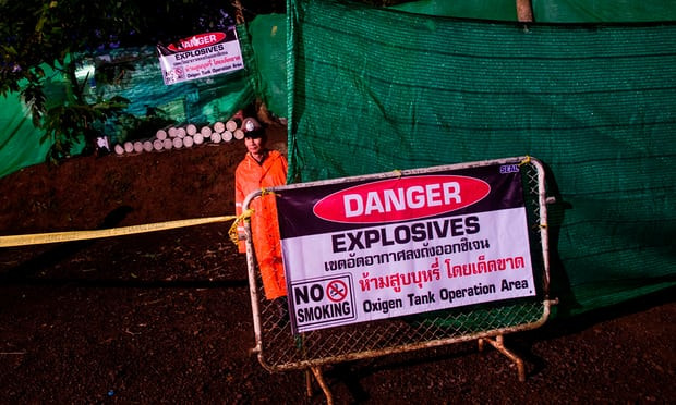 Cảnh sát Thái đứng canh ngoài cửa hang. Biển cảnh báo nguy hiểm (Ảnh Reuters)