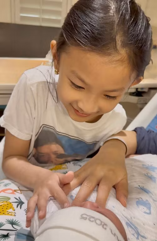 Bé Phoebe cưng nựng em trai vừa chào đời. Ảnh: FB Lam Trường.