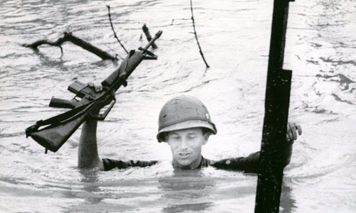 Một lính Mỹ di chuyển qua khu vực nước ngập đến cổ. Binh sĩ này giơ cao vũ khí để chúng không bị nước ngấm vào.