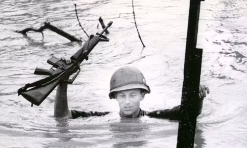 Một lính Mỹ di chuyển qua khu vực nước ngập đến cổ. Binh sĩ này giơ cao vũ khí để chúng không bị nước ngấm vào.