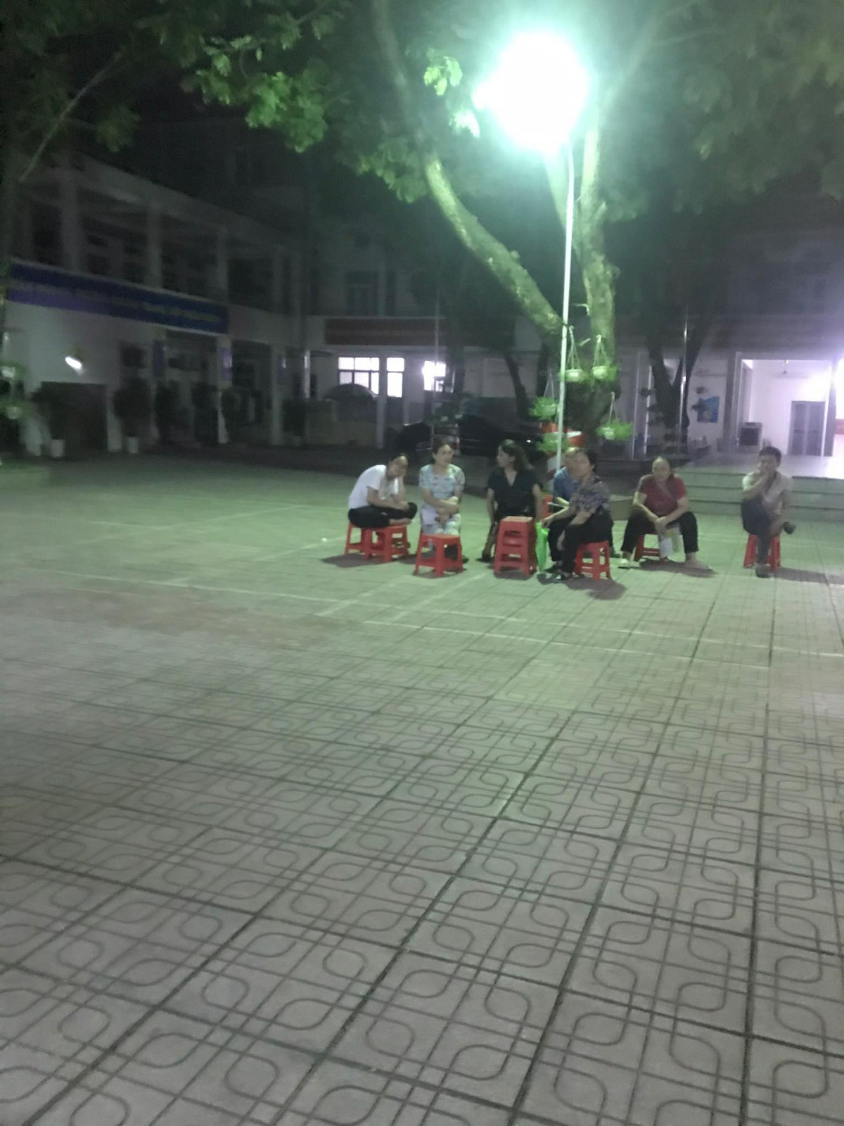 Trường THPT Hoàng Cầu hoạt động theo mô hình công lập tự chủ tài chính từ năm 2012. Một nhóm phụ huynh ngồi chờ nộp hồ sơ vào lớp 10 cho con trong sân trường.