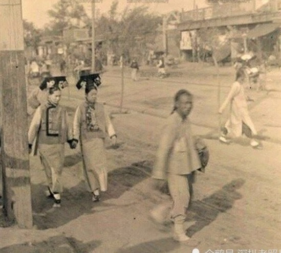 Hai phụ nữ mặc trang phục truyền thống của nhà Thanh bước đi uyển chuyển trên đường phố.