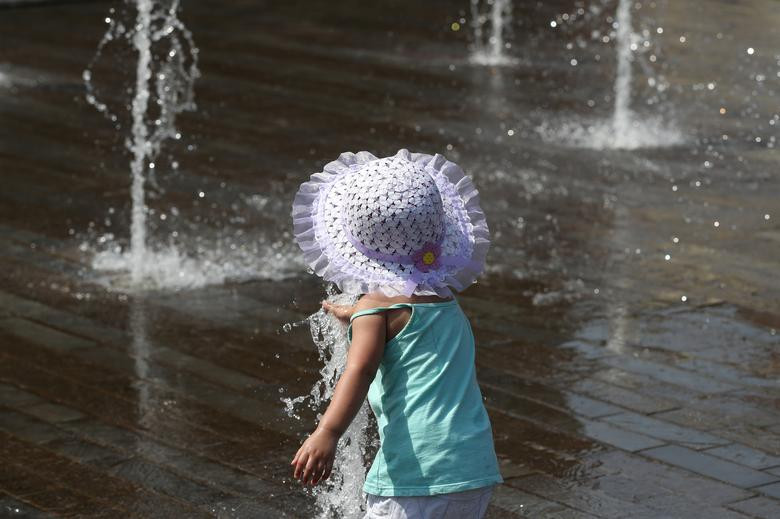 Một bé gái chơi đùa ở đài phun nước tại Brussels, Bỉ.