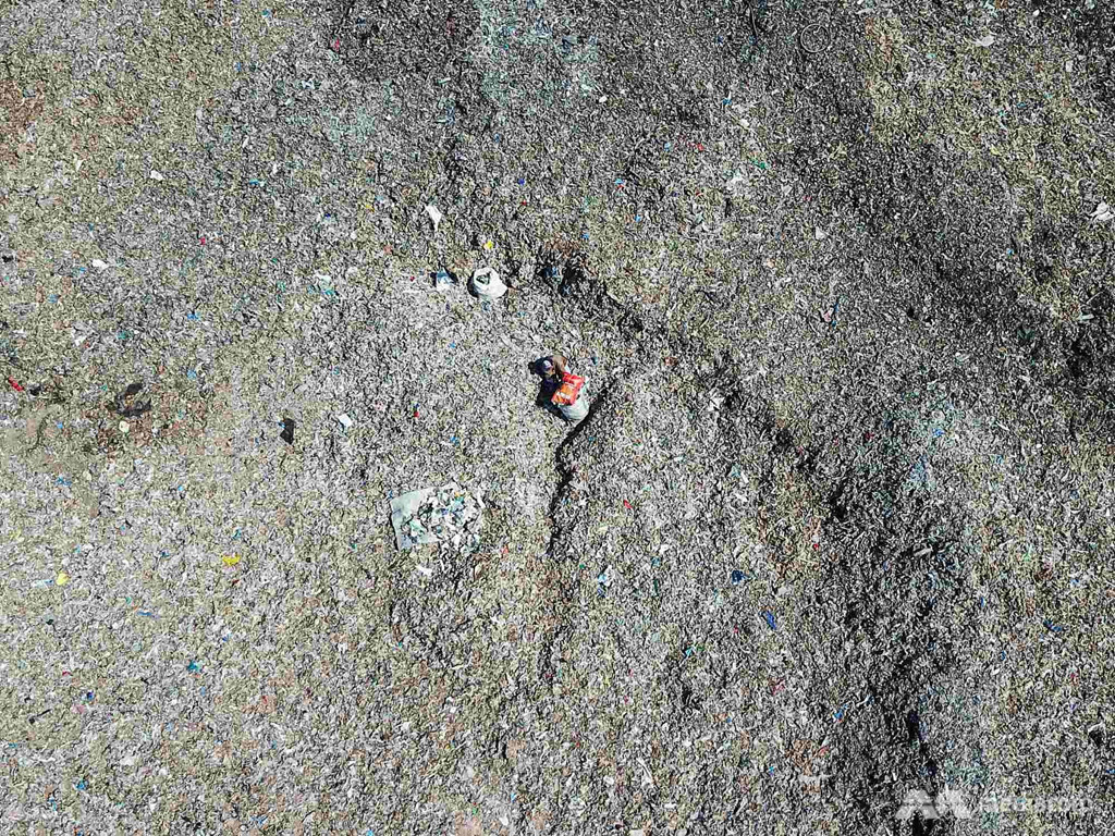 Bất chấp ảnh hưởng tới cảnh quan đường phố cũng như tác động tiêu cực tiềm tàng với sức khỏe, người dân ở Bangun "nghiện" ngồi giữa đống rác thải chất chồng trước cửa nhà và làm công việc mang lại thu nhập chính: phân loại rác thải nhựa. Nhiều gia đình đã bán hoặc chuyển đổi mục đích sử dụng những mảnh đất để làm nơi chứa rác thải nhựa. "Tôi từng là nông dân, nhưng nay tôi quyết định chuyển sang phân loại rác. Làm việc này kiếm được kha khá tiền", Supriadi, người đàn ông 42 tuổi có nhà tại Bangun, cho biết. Ảnh: CNA.