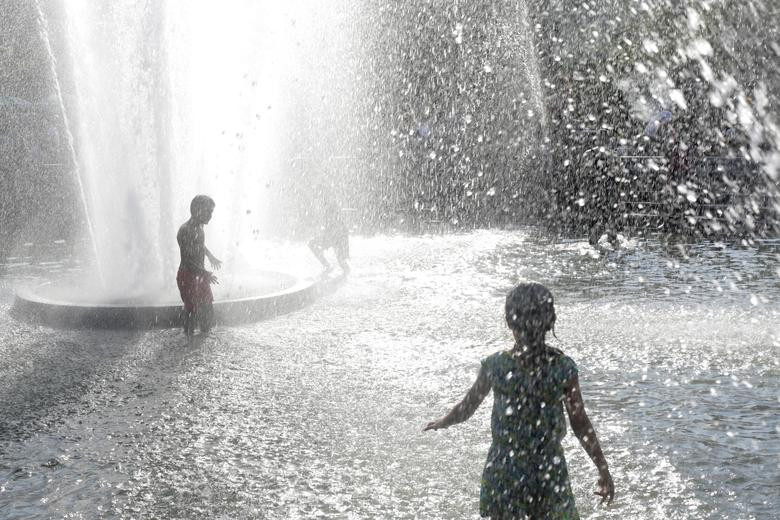 Người dân chơi đùa dưới đài phun nước tại Manhattan hôm 20/7.