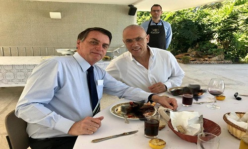 Đại sứ Israel Yossi Shelley (phải) và Tổng thống Brazil Jair Bolsonaro cùng thưởng thức bữa ăn trước trận đấu bóng đá giữa hai đội tuyển Brazil - Peru vào ngày 7/7. Đại sứ quán Israel tại Brazil sau đó đã đăng tải lên trang cá nhân Twitter bức ảnh ghi lại khoảnh khắc hai người cùng dùng bữa kèm dòng trạng thái cổ vũ đội tuyển Brazil. Đặc biệt trong bức ảnh, đĩa thức ăn của cả hai bị bôi đen.