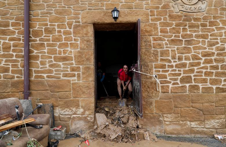 Người phụ nữ dọn dẹp đống bùn đất trong nhà của cô ở Pueyo.